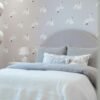 A cozy bedroom with swan-patterned wallpaper and a plush bed.
