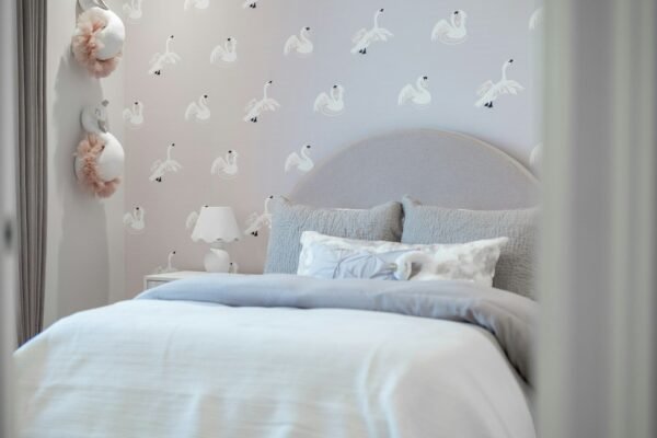 A cozy bedroom with swan-patterned wallpaper and a plush bed.